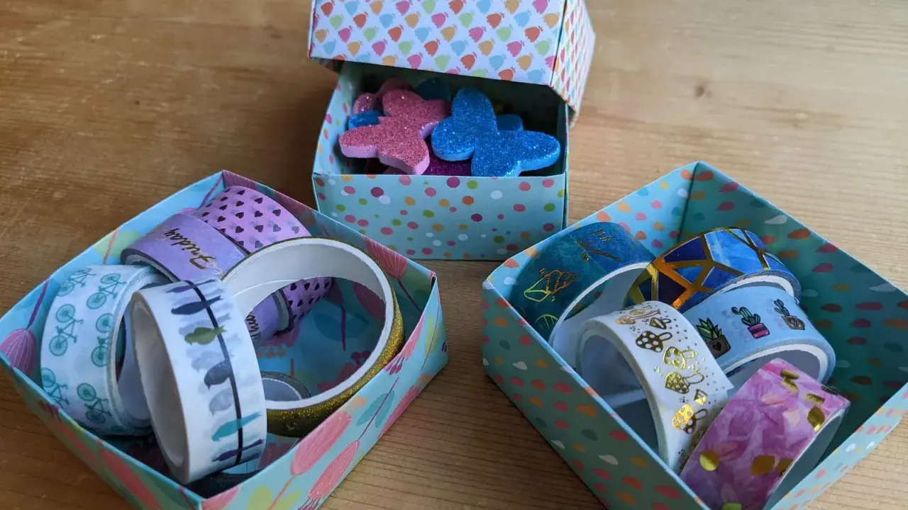 Bunte schachtel falten mit deckel, gefüllt mit Washi-Tapes und Glitzer-Schmetterlingen.