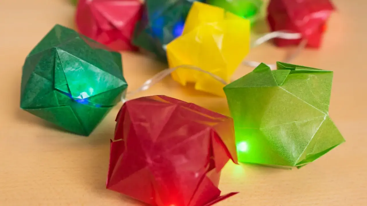 Bunte Origami-Würfel leuchten auf einer Lichterkette. Eine Anleitung für diese origami lichterkette anleitung wäre toll.