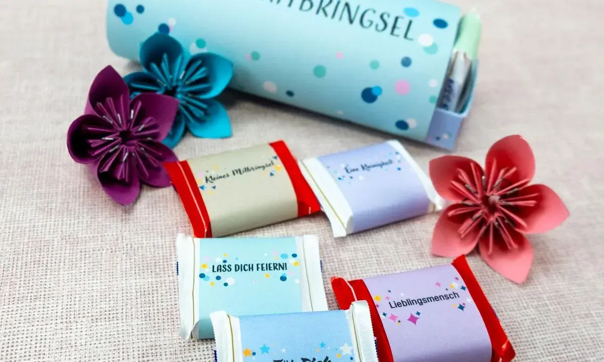 Kleine Schokoladen-Geschenke zum Basteln mit lieben Botschaften wie "Lieblingsmensch" und bunten Origami-Blumen.
