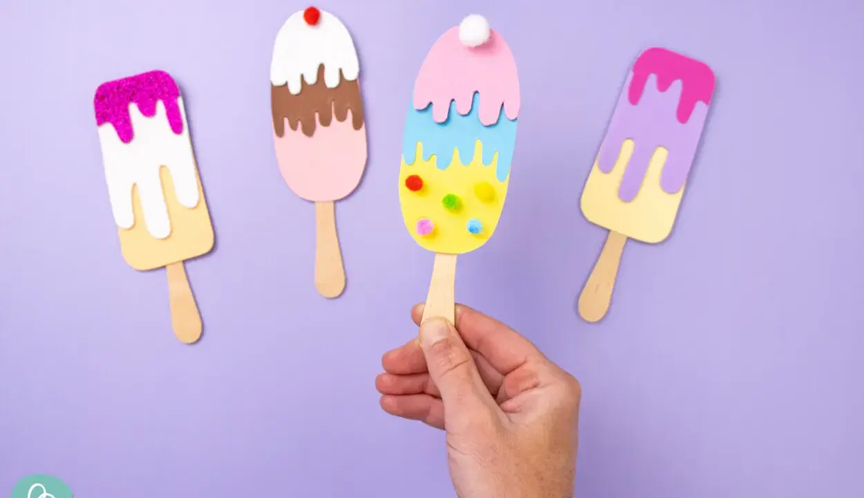 Bunte Eis-Bastelvorlagen: vier selbstgemachte Eis am Stiel aus Papier, dekoriert mit Glitzer und Pompons.