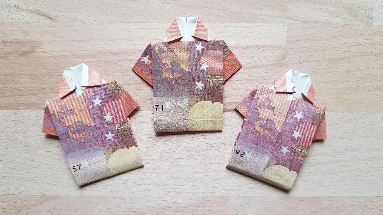 Drei Origami-Hemden aus Geldscheinen. Das letzte Hemd falten ist eine Kunst für sich.