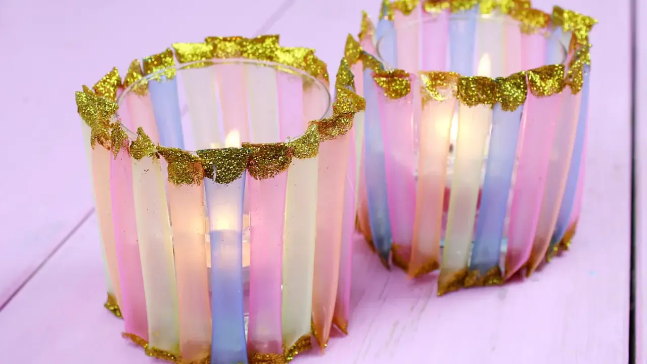 Zwei bunte Windlichter, die Kinder mit Papier und Glitzer basteln können. Sie leuchten sanft.