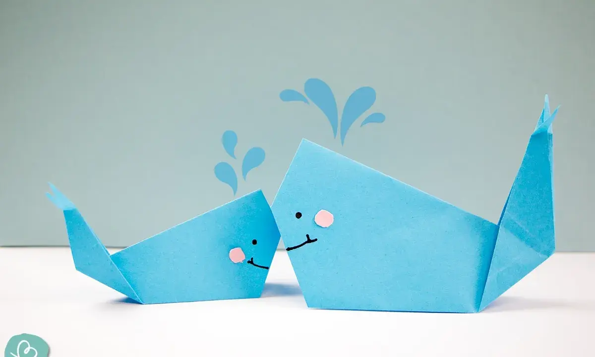 Zwei niedliche Origami-Wale, die Wasser spritzen.