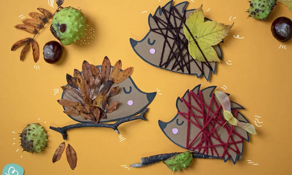 Drei Igel-Bastelvorlagen aus Papier mit Blättern, Garn und Ästen. Ein Igel hat braunes Garn, ein anderer Herbstblätter, der dritte ist mit roten Garn verziert.