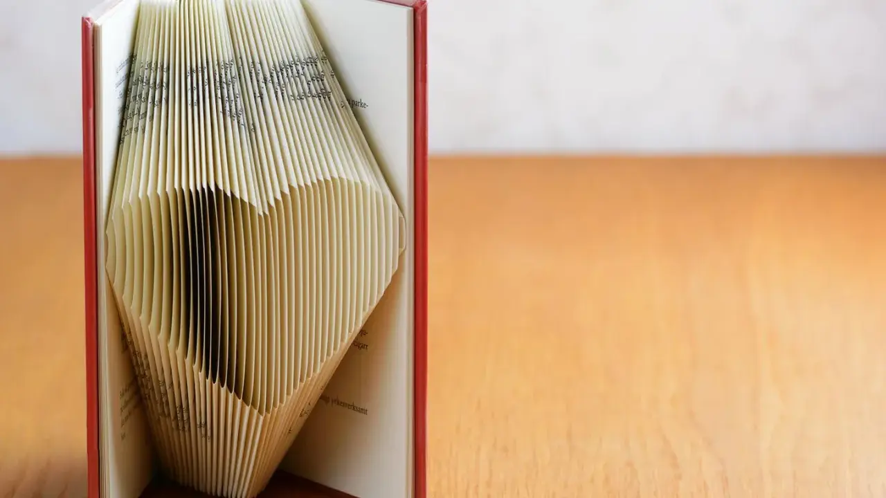 Ein Buch, dessen Seiten zu einem Herz gefaltet sind. Eine kreative Idee für ein Geldgeschenk, Buch basteln.