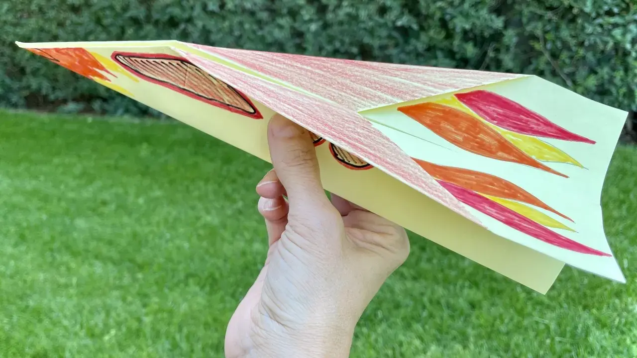 Bunter Papierflieger mit Flammenmuster, bereit zum Abheben. Hier ist die papierflieger anleitung zum ausdrucken.
