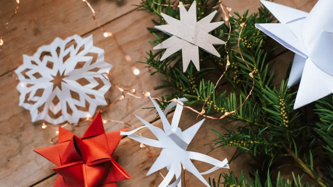 Zauberhafte Papier bastelideen Weihnachten einfach: Sterne aus Papier, Tannenzweige und Lichterkette auf Holz.