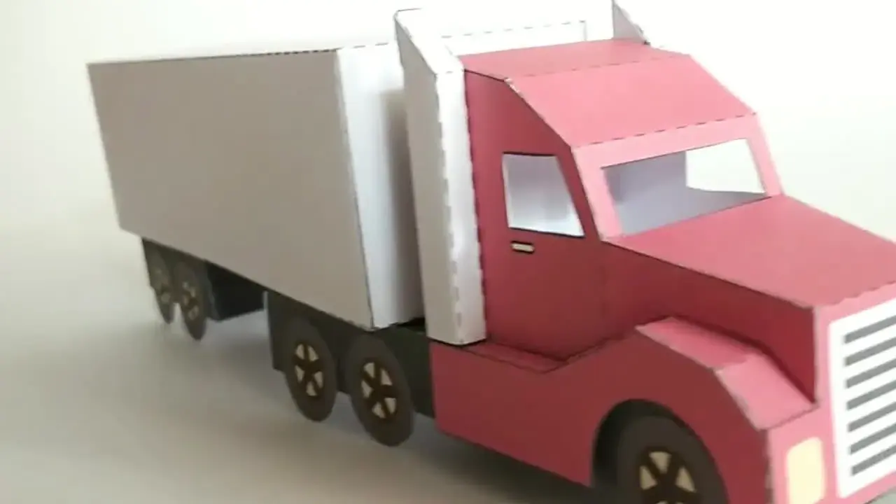 Ein roter LKW mit weißem Auflieger, liebevoll aus Papier gebastelt.