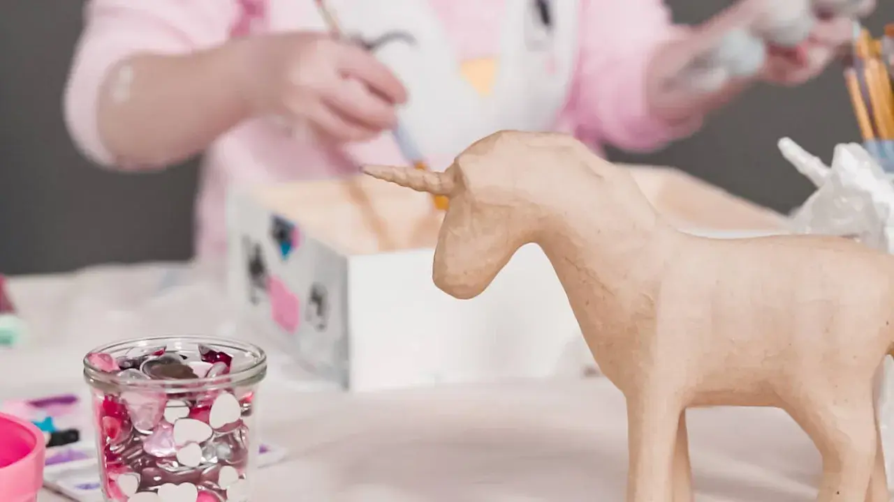 Ein Kind bastelt einfache Pappmache Figuren, hier ein Einhorn.