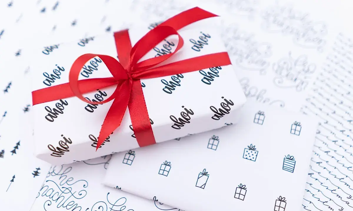 Geschenkpapier zum ausdrucken mit "ahoi" und kleinen Geschenken. Perfekt für maritime Weihnachtsgrüße.