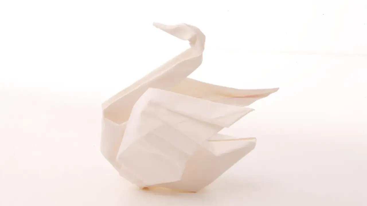 Ein weißer Origami-Schwan, der Eleganz und Reinheit symbolisiert. Die Bedeutung des Origami-Schwan steht für Glück und Treue.