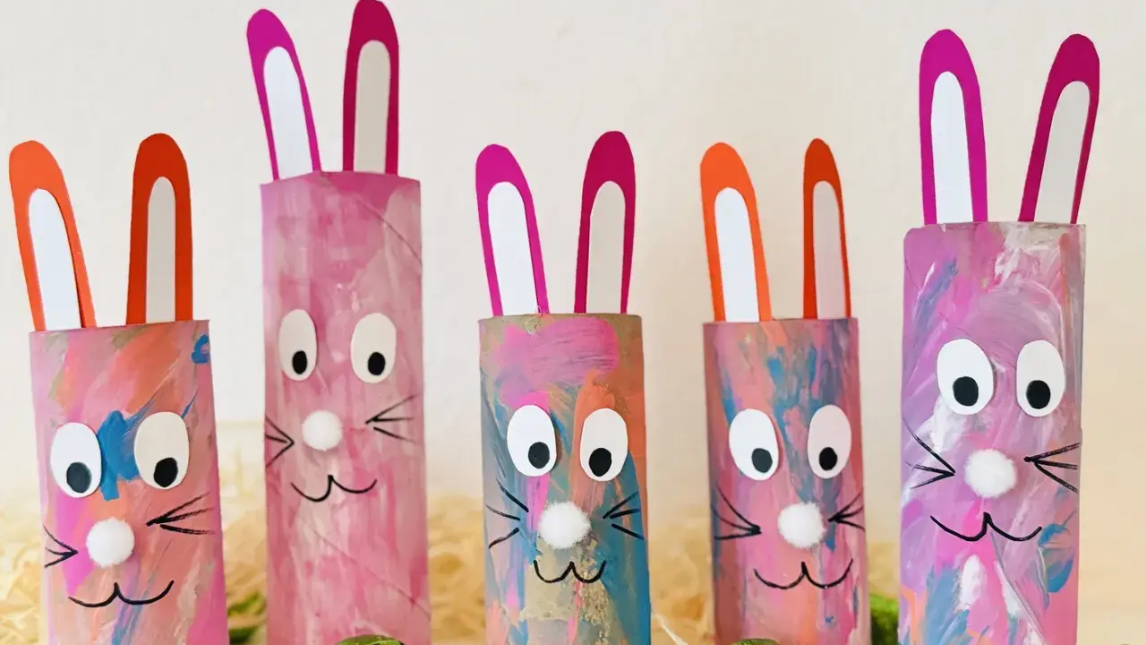 Fünf bunte Osterhasen aus Klopapierrollen mit großen Augen und rosa Ohren, dekoriert mit Pinselstrichen.