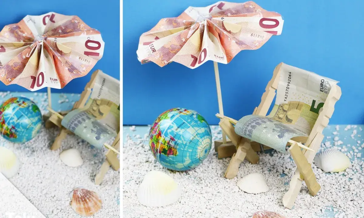 Kreative Ideen: Anker falten Geld zu einer Mini-Strandkulisse mit Liegestuhl und Sonnenschirm aus Euroscheinen.