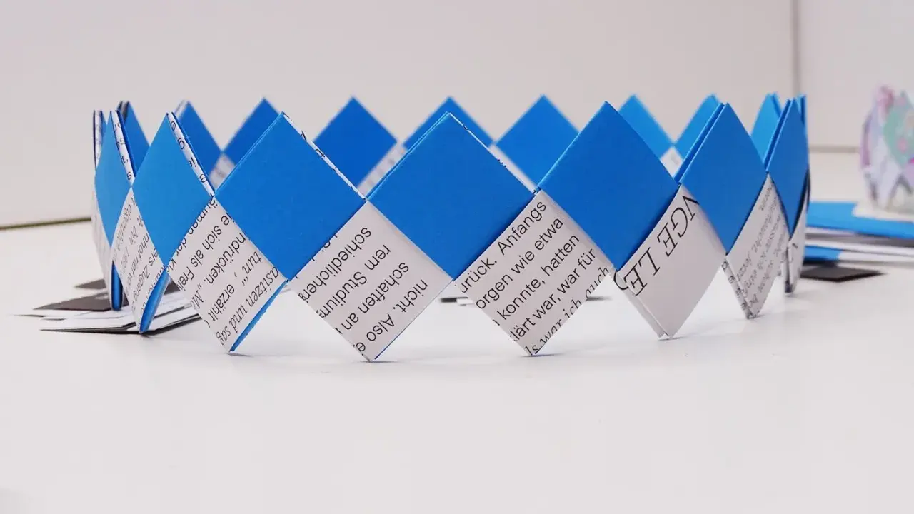 Eine selbstgebastelte Geburtstagskrone aus Papierstreifen, blau und weiß, mit Text bedruckt. Perfekt zum Geburtstagskrone basteln!