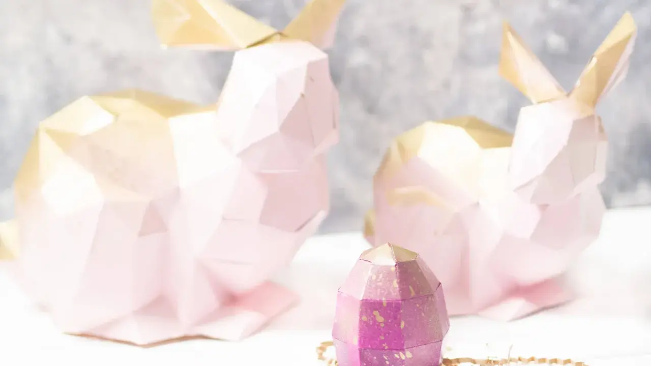 Zwei rosa 3D Origami Hasen mit goldenen Ohren und ein lila Ei. Eine Anleitung für 3d origami hase anleitung wäre hier toll.