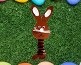 Brauner Papierhase mit Ziehharmonika-Körper, ein süßes Beispiel für Osterhasen basteln, auf grünem Kunstrasen mit bunten Eiern.