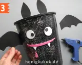 Schritt 3: Ein Fledermaus-Eimer für Halloween basteln. Mit Heißkleber und Bastelmaterialien entsteht ein gruseliger Hingucker.