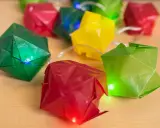 Bunte Origami-Würfel leuchten auf einer Lichterkette. Eine Anleitung für diese origami lichterkette anleitung wäre toll.