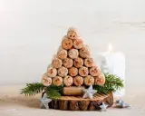 Weihnachtsbaum aus Korken, ein tolles Bastelprojekt für Erwachsene. Mit Tannenzweigen und Sternen dekoriert, neben einer Kerze.