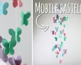 Bunte Schmetterlinge aus Papier hängen an Schnüren und bilden ein Mobile. Hier gibt es kostenlose mobile basteln vorlagen!