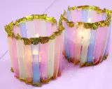 Zwei bunte Windlichter, die Kinder mit Papier und Glitzer basteln können. Sie leuchten sanft.