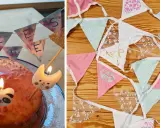 Geburtstagskuchen mit Kerzen und einer selbstgebastelten Papierkette. Daneben liegen weitere bunte Wimpelketten zum Basteln.