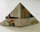 Ein dreieckiger Papierhut, gefaltet aus Zeitungspapier mit Werbung für Käse und Kaffee. Das Papierhut falten ist eine einfache Bastelidee.