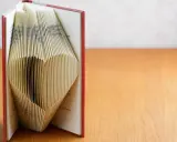 Ein Buch, dessen Seiten zu einem Herz gefaltet sind. Eine kreative Idee für ein Geldgeschenk, Buch basteln.