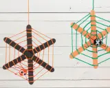 Zwei selbstgebastelte Spinnennetze aus Eisstielen und Wolle, mit kleinen Spinnen und Kulleraugen. Perfekt zum Spinnennetz basteln für Halloween!