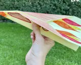 Bunter Papierflieger mit Flammenmuster, bereit zum Abheben. Hier ist die papierflieger anleitung zum ausdrucken.