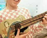 Kind bastelt Gitarre nach Vorlage. Die selbstgemachte Gitarre ist mit süßen Tieren wie Pinguin, Panda, Hase und Fuchs bemalt.