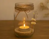 Ein Glas mit Sand, Teelicht und getrockneten Blumen. Mit Juteband und Schleife verziert – so einfach lassen sich schöne Teelichthalter basteln.