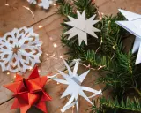 Zauberhafte Papier bastelideen Weihnachten einfach: Sterne aus Papier, Tannenzweige und Lichterkette auf Holz.