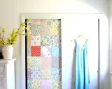 Kreatives Basteln mit Tapetenresten: Ein Patchwork-Muster ziert die Tür eines Schranks. Daneben hängt ein hellblaues Kleid.