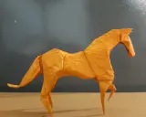 Ein orangefarbenes Origami-Pferd steht auf einem Tisch.