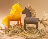 Zwei selbstgebastelte Pferde, eine gelbe und eine braune pferd vorlage, stehen auf Stroh.