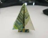 Ein kleiner, gefalteter Baum aus Geldscheinen steht auf einem Tisch. Ein kreativer geld falten baum.