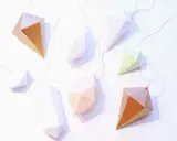 Papierdiamanten in verschiedenen Farben und Größen, die an goldenen Fäden hängen. Eine tolle Idee für eine diamant basteln vorlage.