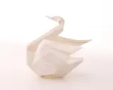 Ein weißer Origami-Schwan, der Eleganz und Reinheit symbolisiert. Die Bedeutung des Origami-Schwan steht für Glück und Treue.