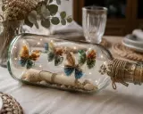 Eine Flaschenpost basteln: Eine Glasflasche gefüllt mit Muscheln, einer Schriftrolle, Lichterkette und gefalteten Schmetterlingen aus Geldscheinen.