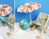 Kreative Ideen: Anker falten Geld zu einer Mini-Strandkulisse mit Liegestuhl und Sonnenschirm aus Euroscheinen.