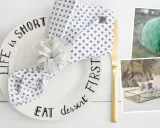 Tischdeko mit Teller "Life is short, eat dessert first", Serviettenring und Kerzen. Ideen zum **Wellen basteln** für eine festliche Tafel.