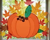 Herbstliche Fensterdeko basteln mit Kindern: Vorlagen für bunte Blätter und einen großen Kürbis schmücken das Fenster.