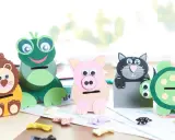 Vier selbstgebastelte Spardosen in Tierform: Löwe, Frosch, Schwein und Katze. Eine Schildkröte steht daneben.