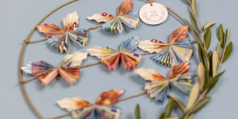 Kreative Deko: Viele bunte Schmetterlinge, gefaltet aus Geld, hängen an einem Ring. Ein schönes Geschenk, um Freude zu schenken.
