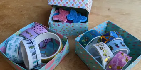 Bunte schachtel falten mit deckel, gefüllt mit Washi-Tapes und Glitzer-Schmetterlingen.