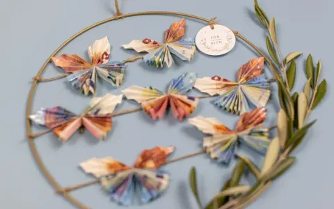 Kreative Deko: Viele bunte Schmetterlinge, gefaltet aus Geld, hängen an einem Ring. Ein schönes Geschenk, um Freude zu schenken.