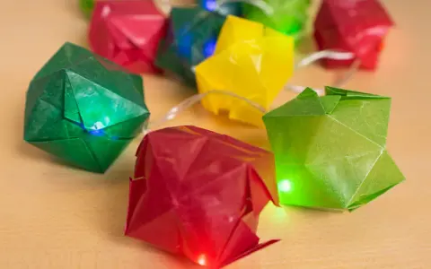 Bunte Origami-Würfel leuchten auf einer Lichterkette. Eine Anleitung für diese origami lichterkette anleitung wäre toll.