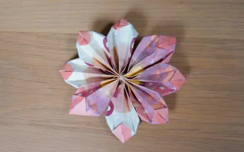 Eine kunstvolle Geld falten Tulpe aus Euro-Scheinen, die auf einer Holzoberfläche liegt.