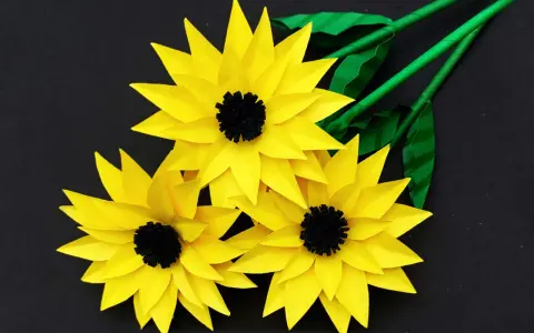 Drei gelbe Papier-Sonnenblumen mit schwarzen Zentren und grünen Stielen, ideal als sonnenblume basteln vorlage.